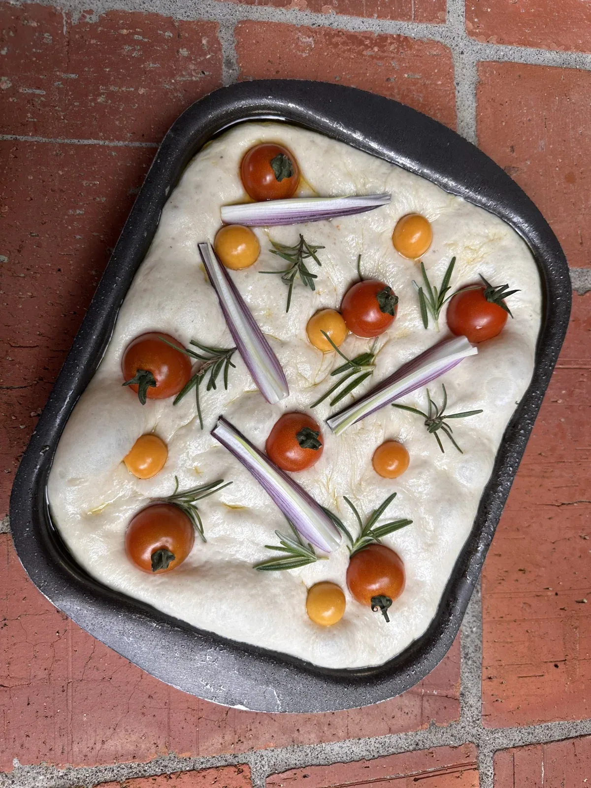 Fresh focaccia dough with tomatoes and rosemary
